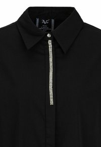 Black shirt made of smooth fabric featuring a pointed collar and a central line of sparkling rhinestones along the button placket.