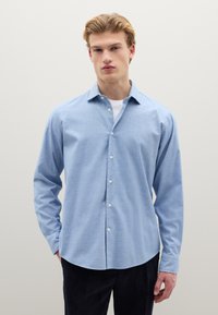 Camicia celeste con bottoni, realizzata in tessuto morbido, con colletto classico, maniche lunghe e orlo dritto.