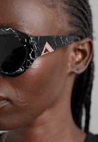 Black sunglasses with a marble-patterned frame and rose gold accents. Lenses are dark and round; frame features angular silhouettes.