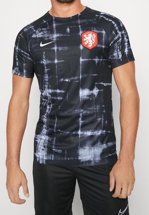 Black short-sleeve sports shirt with a textured, tie-dye pattern in gray. Features a red lion emblem and Nike logo on the chest.