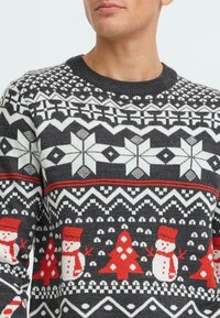 Knit holiday sweater featuring a black base, white and red geometric patterns, snowflakes, snowmen, and Christmas trees. Round neckline.