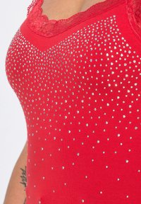 Top rosso senza maniche con scollatura in pizzo, decorato con strass argentati sparsi, che offre una texture liscia e un design aderente.