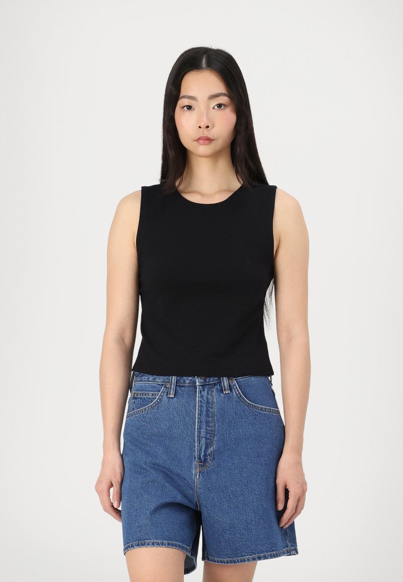 Black sleeveless top made of smooth fabric, paired with high-waisted blue denim shorts featuring a classic five-pocket design and cuffed hem.