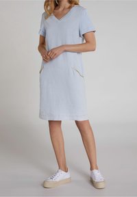 Lichtblauwe jurk met korte mouwen en een V-hals, met zijzakken versierd met een decoratieve kettingdetail. Gladde stof met een ontspannen pasvorm.