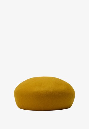 Puf w kolorze musztardowym, wykonany z miękkiego filcu. O okrągłym kształcie, z gładką teksturą i minimalistycznym designem, odpowiedni do różnych wnętrz.