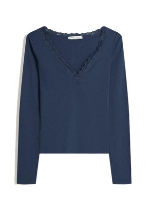 Marineblå langærmet top med V-hals, der har en bølget blondedetalje. Blødt stof med en tætsiddende pasform og slidser i siderne ved kanten.