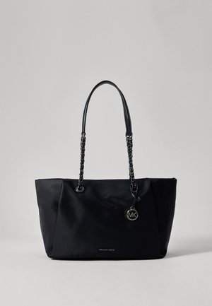 Sac cabas noir Michael Kors avec chaîne, doubles poignées en cuir et un pendentif rond avec le logo MK sur un fond gris.