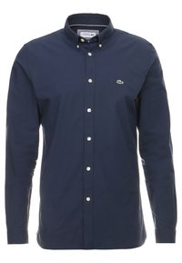 Marineblauw overhemd met knopen, gemaakt van katoen, met een klassieke kraag, witte knopen en een klein groen geborduurd logo op de borst.