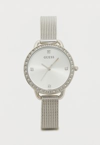 Relógio com pulseira de malha prata e mostrador redondo branco, adornado com cristais transparentes, apresentando ponteiros prateados e o logotipo da GUESS ao centro.