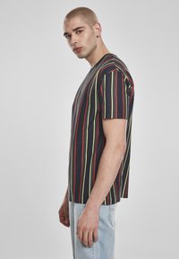 T-shirt rayé en bleu marine avec des lignes verticales rouges, jaunes et vertes, fabriquée en coton, dotée d'une coupe décontractée et d'un col rond.