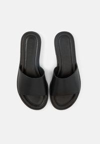 Ζευγάρι μαύρων σανδαλιών τύπου slide με φαρδιές λουριά και μαλακές σόλες, εμφανιζόμενα από πάνω σε λευκό φόντο.