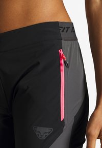 Black athletic shorts with contrasting dark gray panels, featuring a bright pink zip pocket and a subtle logo on the waistband.