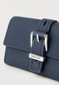 Portafoglio in pelle blu con finitura testurizzata, caratterizzato da una fibbia hardware argentata e una targhetta con il logo frontale. Design compatto con linee pulite.