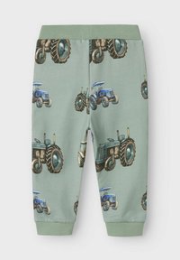 Pantaloni della tuta verdi in cotone con un motivo a trattore ripetuto, dotati di polsini e vita a costine, e una texture liscia.