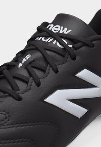 Baskets New Balance 442 noires avec logo blanc sur le côté et lacets noirs assortis noués sur une tige en cuir texturé.