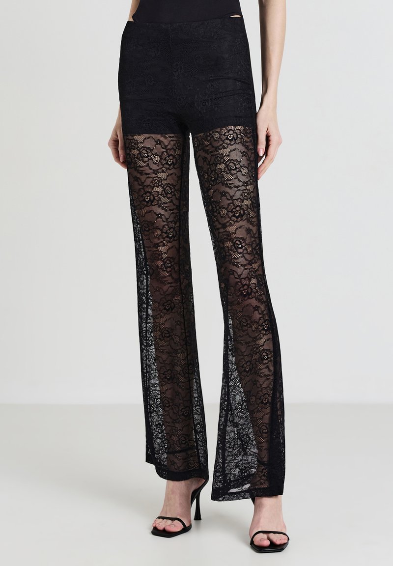 Pantaloni in pizzo nero con vita aderente e design a gamba svasata, con sovrapposizione in pizzo trasparente e dettagli a motivo floreale.