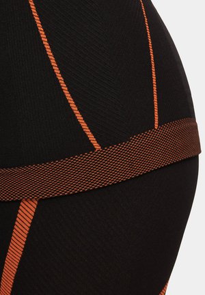 Czarne legginsy sportowe z teksturowanej tkaniny, z żywymi pomarańczowymi paskami i wzorzystym elastycznym pasem w talii. Zbliżenie na szczegóły.