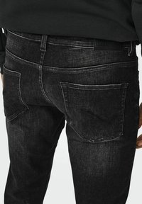 Jeansi negri din denim cu o croială slim, având un finisaj texturat, buzunare la spate și o etichetă din piele neagră cu "ONLY & SONS" aproape de talie.