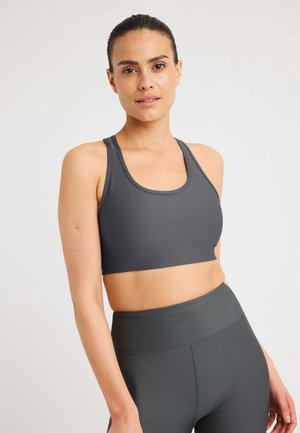 Grijze geribbelde sportbh met een ronde halslijn en brede bandjes, gecombineerd met bijpassende high-waisted leggings, gemaakt van een gestructureerde stof.