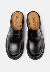 Scarpe slip-on nere in pelle con punta arrotondata e una vistosa striscia decorativa. Soletta marrone con il marchio "CAMPER". Suola texturizzata.