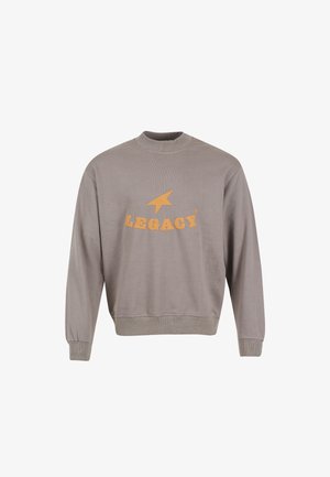 Pilkas džemperis, pagamintas iš minkštos medžiagos, su apvaliu iškirpimu, ilgomis rankovėmis ir oranžiniu „LEGACY“ logotipu su žvaigždės dizainu priekyje.