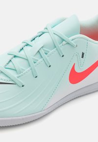 Világoskék sportcipő, strukturált szintetikus felsőrész, fehér talp, rózsaszín Nike logó, és lapos fűzőkkel. Masszív és áramvonalas kialakítással rendelkezik.