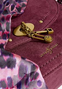 Borsa in suede color bordeaux con hardware dorato, caratterizzata da una chiusura decorativa e una sciarpa a motivo rosa e viola drappeggiata sopra.