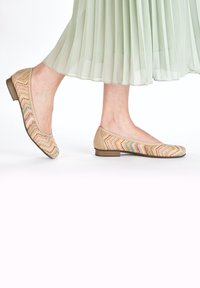 Beige Ballerinas mit einem strukturierten, mehrfarbigen Zickzackmuster auf dem Obermaterial und einem niedrigen braunen Absatz, kombiniert mit einem plissierten mintgrünen Rock.