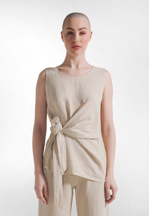 Beige mouwloze top van gestructureerde stof, met een knoopdetail aan de voorkant en een ontspannen pasvorm. Eenvoudige ronde halslijn en langere zoom aan de achterkant.