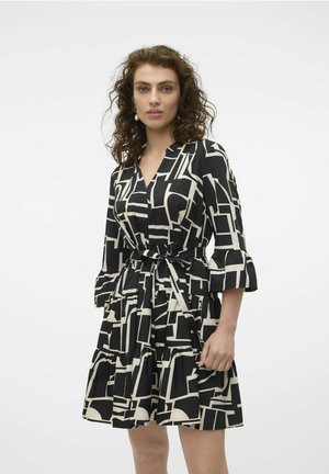 Robe à motifs noir et blanc avec une ceinture, manches trois-quarts, jupe à volants et décolleté en V. Texture de tissu lisse.