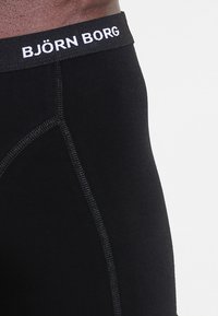 Fekete boxernadrág, szőtt elasztikus derékszíjjal, amelyen fehér színnel szerepel a "BJÖRN BORG" felirat. Sima anyag, lapos varrásokkal. Nincsenek minták.
