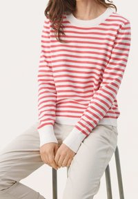 Rød og hvidstribet sweater med rund halsudskæring og ribbede manchetter, parret med beige bukser. Blød tekstur og afslappet pasform.