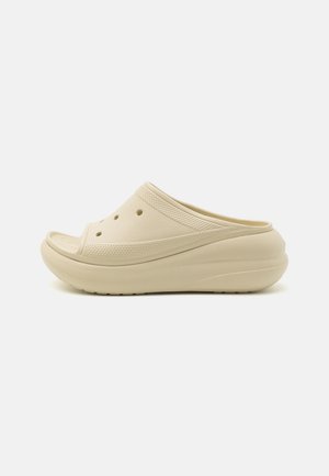Sabot beige à enfiler avec des trous de ventilation, bande supérieure texturée et semelle épaisse rembourrée, présenté en profil sur un fond uni.