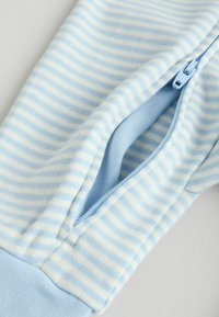 Svetlomodrá pruhovaná látka s mäkkou textúrou. Obsahuje zips v rovnakej modrej farbe pozdĺž bočného šva.