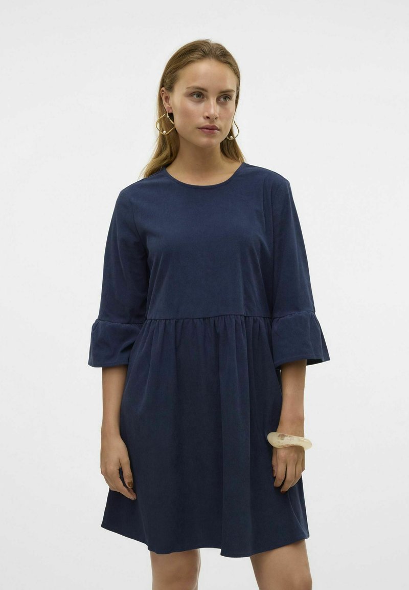 Mörkblå klänning i knälängd med rund halsringning och 3/4-långa ärmar som har volangärmar och ett rynkat midjeband. Slät textur.