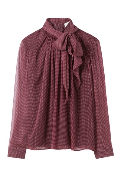 Blusa color burdeos con un lazo en el cuello, con un diseño de pliegues fruncidos y pequeños lunares blancos en una tela transparente. Mangas largas.
