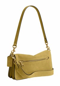 Sac à épaule en daim jaune doux avec poche zippée dorée, bretelles détachables et une étiquette en cuir de marque.