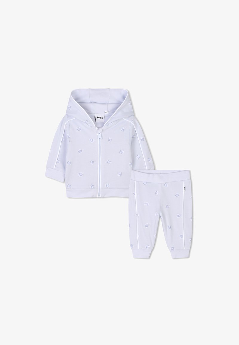 Fato de treino infantil em duas peças, branco, com uma hoodie com fecho éclair de textura suave e padrão de logotipo azul, complementado por calças combinando com cintura elástica.