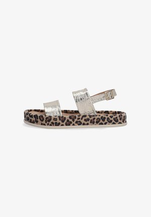 Metalické stříbrné sandály se dvěma širokými pásky. Podešev má béžový základ s leopardím vzorem. Uzávěr na přezku je na zadním pásku.