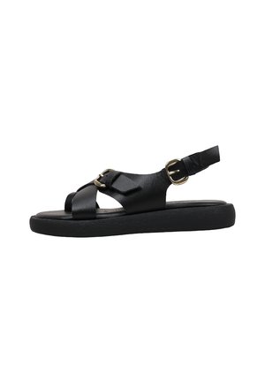 Sandale plate noire avec deux boucles dorées, bout ouvert et bride arrière pour le maintien de la cheville, présentée sur un fond blanc.