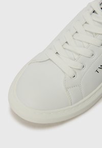 Hvit sneakers laget av glatt skinn med rund tå, snøring foran og minimal søm. Har en teksturert gummisåle og logo-detallle.
