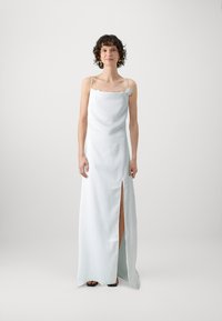 Vit satin maxi-klänning med en vågig halsringning och en enskild dekorativ blomma; har en hög slits vid låret och tunna axelband.