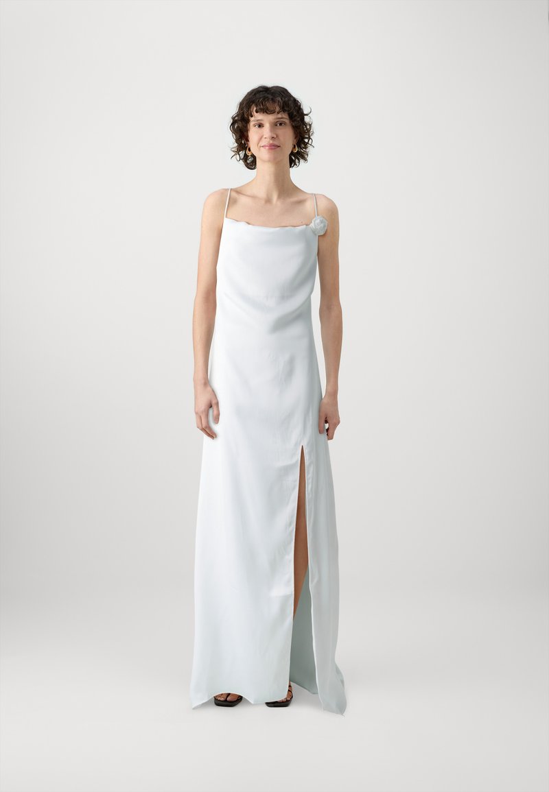 Vit satin maxi-klänning med en vågig halsringning och en enskild dekorativ blomma; har en hög slits vid låret och tunna axelband.
