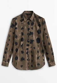 Pitkähihaista paitaa oliivinvihreässä kankaassa, jossa on mustia abstrakteja laikkuja ja napitettavat etuosat. Kankaassa on sileä rakenne ja klassinen kaulustyyny.