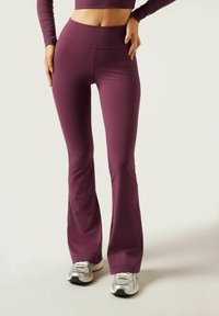 Flared athletic pants in a deep burgundy color, made of stretchy fabric, featuring a high waistband and fitted design throughout the legs.