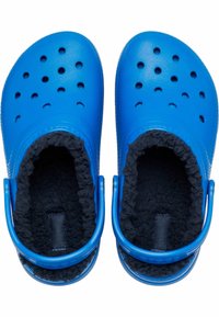 Blaue Clogs mit Belüftungslöchern, flauschigem schwarzen Futter und kontrastierenden strukturierten Sohlen. Mit einem Fersenriemen für einen sicheren Sitz.