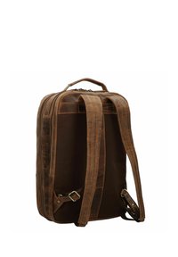 Sac à dos en cuir marron et toile avec une silhouette structurée, deux bretelles rembourrées, une poignée supérieure et des détails de boucle ajustables sur les côtés.