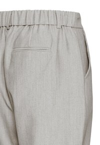 Světle šedé kalhoty z texturované látky s elastickým pasem a bočními kapsami. Mají jednu zadní kapsu s jemným švem.