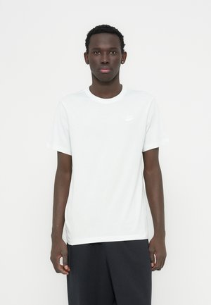 Hvid t-shirt med rund hals i bomuld, korte ærmer, med en lille hvid Nike-logo på venstre side af brystet.