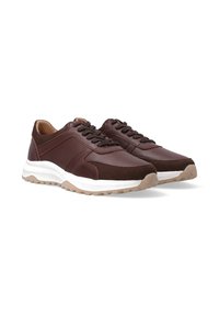 Para ciemno-brązowych skórzanych sneakersów z białymi, masywnymi podeszwami i beżową, rowkowaną podeszwą na białym tle.